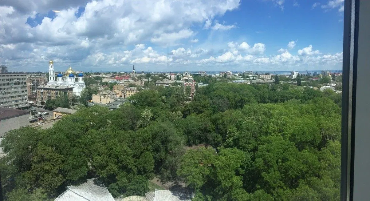 

City skyline w/ clouds, buildings, trees: peaceful urban escape.